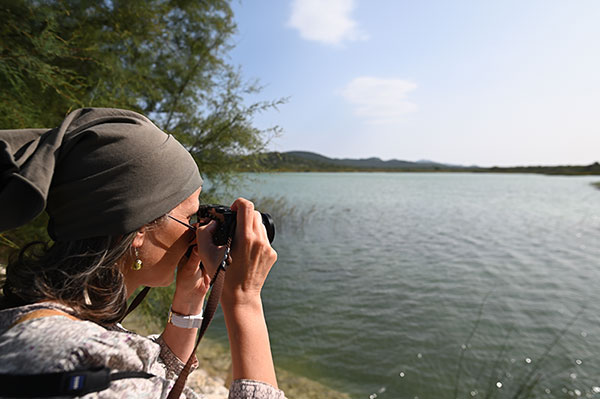 Weitläufiger See, links unten bin ich im Bild seitlich zu sehen wie ich die Kamera in der Hand halte. Ich trage eine Kopfbedeckung und Sonnenbrille.